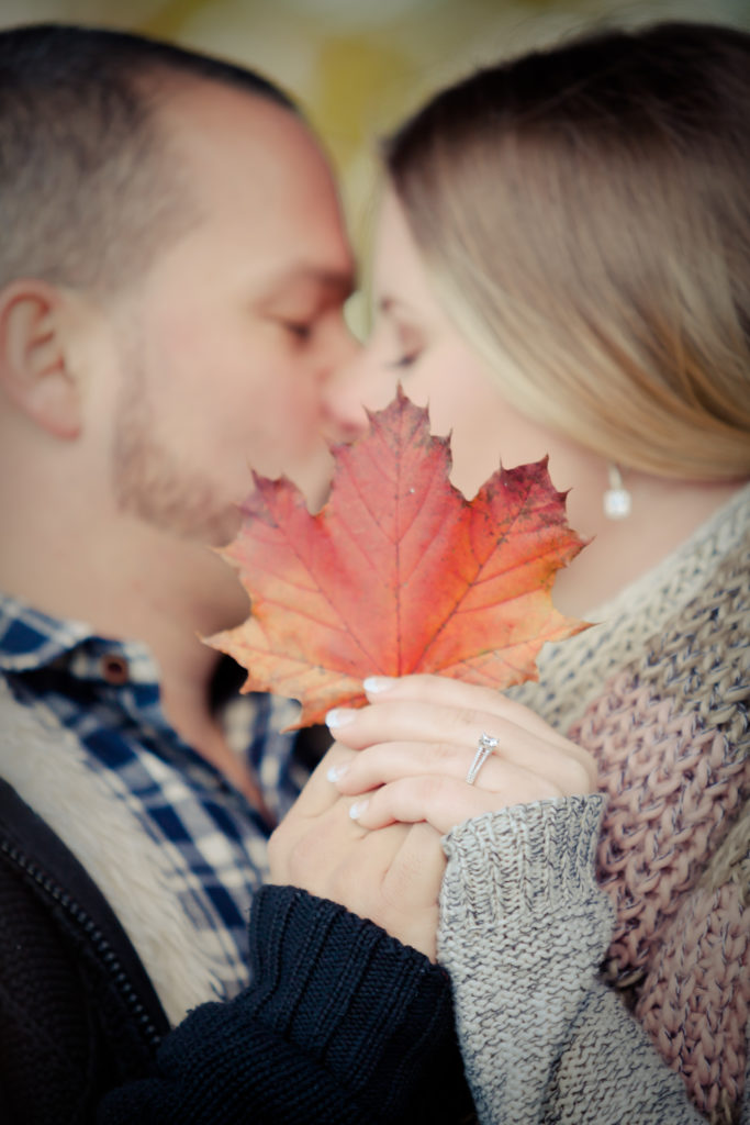 Couple kissing behind an orange maple leaf