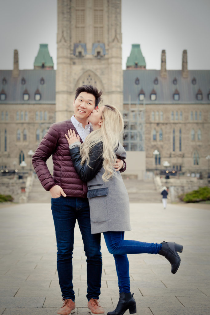 Engaged couple kissing in front of the Peace tower at Parliment Hill Ottawa