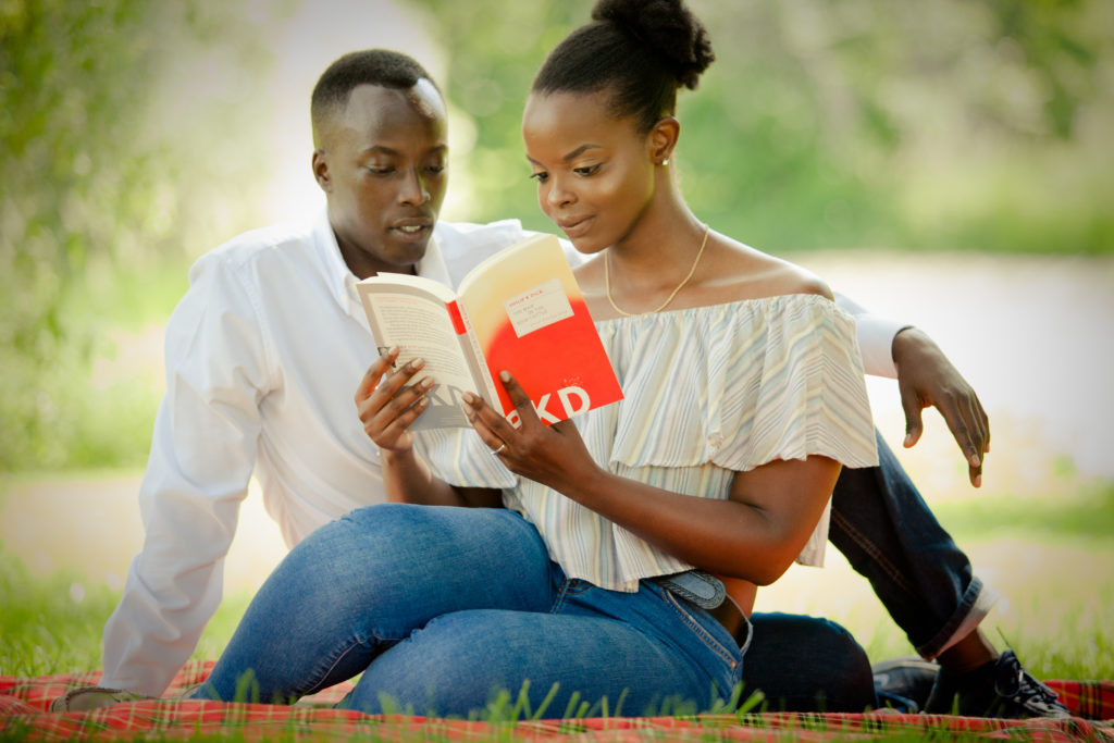 Engaged couple sitting on a blanket reading a book together